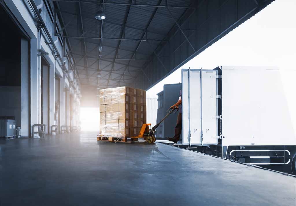Pracovník skladu nakládá paletu zboží do nákladního vozu v logistickém centru