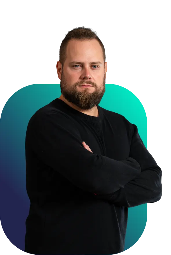 Štěpán, externí designér Better Industry v černém svetru s rukama založenýma na hrudi před tyrkysovo-modrým pozadím“