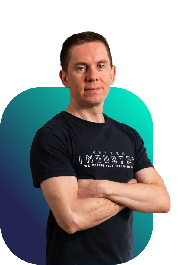 Tomáš, seniorní full‑stack programátor Better Industry v černém tričku s rukama založenýma na hrudi před tyrkysovo-modrým pozadím“